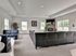 Spacious and stylish living room with sleek black leather seating, modern fireplace, and large windows inviting natural light.