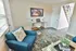 Inviting modern living room with sleek hardwood floors, a stylish blue armchair, and a decorative coffee table, perfect for relaxation.