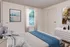 Elegant bedroom with a cozy gray-themed design, featuring abstract wall art, large window with natural light, and modern decor.
