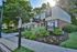 Charming leasing office surrounded by lush greenery and vibrant flowers, inviting future residents with a reserved parking area.