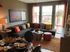 Inviting living room with a modern gray sectional, vibrant cushions, stylish coffee table, and large windows offering city views.