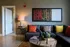 Elegant living room with chic decor, featuring a modern gray sofa accented by vibrant pillows, a stylish side table with a warm lamp, and eye-catching contemporary artwork on the wall.