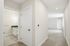 Elegant apartment hallway leading to a modern bathroom, showcasing sleek tile flooring and soft, neutral walls.