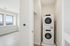 Bright laundry area with modern stacked washer and dryer in a spacious, light-filled apartment.