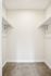Spacious walk-in closet with sleek white shelves and plush carpeting, perfect for ample storage in a modern apartment.