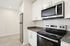 Modern kitchen with sleek stainless steel appliances, including a microwave and oven, set against stylish white cabinetry and pristine countertops.
