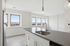 Bright and modern kitchen with sleek stainless steel appliances, elegant countertops, and large windows offering panoramic city views.