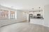 Bright and modern open-concept living area with sleek kitchen, large windows, and stylish pendant lighting.