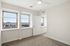Bright and airy bedroom showcasing large windows with stunning city views, sleek ceiling fan, and plush carpeting for ultimate comfort.