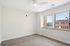 Bright and airy bedroom with large windows, plush carpet, and a ceiling fan, offering a welcoming atmosphere.