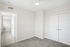 Bright and modern bedroom with plush carpet, ample closet space, and sleek ceiling fan, perfect for comfort and style.