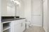 Elegant modern bathroom with sleek black countertop, large mirror, and spacious shower in a bright, airy setting.