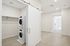 Modern laundry area featuring a stacked washer and dryer with sliding barn door in a spacious, bright apartment hallway.