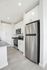 Contemporary kitchen with sleek stainless steel appliances, pristine white cabinetry, and modern gray countertops.