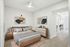 Modern bedroom with minimalist decor, featuring a plush bed, sleek wooden furniture, and contemporary artwork on the walls, leading to an open dining area.