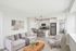 Modern open-concept living room with elegant kitchen, featuring sleek cabinetry, stainless steel appliances, and cozy seating area illuminated by stylish pendant lighting.