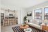 Chic and modern apartment living room with a cozy white sofa, sleek kitchen island with stools, and large sunlit windows.