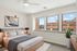 Elegant bedroom with natural light featuring modern decor, comfortable bed, and large windows offering scenic views.