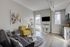 Bright and modern living room with sleek decor, featuring a cozy yellow armchair and elegant glass coffee table, accentuated by natural light from large windows.