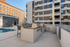 Chic outdoor area featuring modern grills and a refreshing pool next to contemporary apartment buildings.