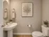 Inviting bathroom with elegant decor, featuring a pedestal sink, a round mirror, and tasteful greenery accents.