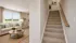 Inviting living room with cozy seating and modern decor beside a staircase, ideal for stylish family living.