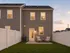 Charming backyard view with cozy outdoor seating area, surrounded by a white fence, against a backdrop of a warm sunset sky and inviting townhouses.
