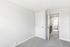 Bright, freshly-painted room with soft carpet flooring leading to a sunlit hallway and modern bathroom.