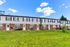 Charming townhouse complex featuring brick and siding exteriors, lush green lawns, and a clear blue sky backdrop.