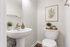 Chic and modern bathroom with stylish decor, featuring a sleek pedestal sink and elegant wall art.