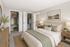 Inviting bedroom with cozy beige bedding, elegant nightstands, and ample closet space, creating a serene and organized retreat.