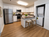 Modern kitchen with stainless steel appliances, sleek countertops, and built-in washer dryer, featuring elegant seating and warm wood flooring.