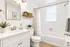 Bright and elegant bathroom with modern fixtures, a classic white vanity, lush greenery, and a serene ambiance.