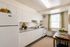 Charming, modern kitchen featuring sleek white cabinets, a cozy dining area, and abundant natural light.