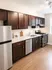 Sleek kitchen with elegant dark wood cabinets, stainless steel appliances, and bright natural lighting.