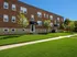 Charming brick apartment building with manicured lawns and lush greenery, offering a serene residential setting.