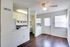 Bright kitchen and dining area featuring modern white cabinetry, stainless steel appliances, and rich wooden flooring.