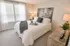 Inviting bedroom with plush white bedding, textured pillows, modern decor, and abundant natural light.