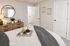 Cozy bedroom with plush decor, featuring a stylish mirror above a rustic wooden dresser, complemented by elegant wall art and soft ambient lighting.