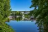 Scenic waterfront view featuring tranquil boats, lush greenery, and charming homes under a clear blue sky.
