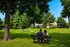 Charming residential area with a lush green park, families enjoying outdoor activities, and cozy homes in the background.