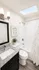 Bright and modern bathroom featuring a sleek granite countertop, elegant white tiles, and a skylight for natural light.