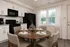 Modern kitchen with sleek black appliances, elegant dining setup, and bright natural light highlighting the stylish decor.