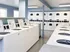 Modern laundry room with multiple washing machines and dryers, featuring bright lighting and sleek design.