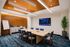 Sophisticated meeting room featuring a large wooden table, stylish chairs, modern lighting, and a digital display with business growth graphs.