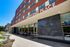 Elegant facade of West End Place showcasing a modern entrance with vibrant outdoor seating and lush surroundings.