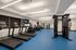 Modern fitness center with state-of-the-art equipment including treadmills, weight machines, and exercise bikes on a sleek blue floor, ideal for active living.