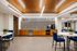 Modern community room with sleek kitchenette, vibrant blue seating, and stylish lighting.