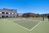 Vibrant outdoor sports court featuring tennis and basketball areas next to modern apartment buildings and lush greenery.