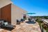 Inviting rooftop terrace with modern lounge chairs, vibrant blue umbrella, and beautiful cityscape views.